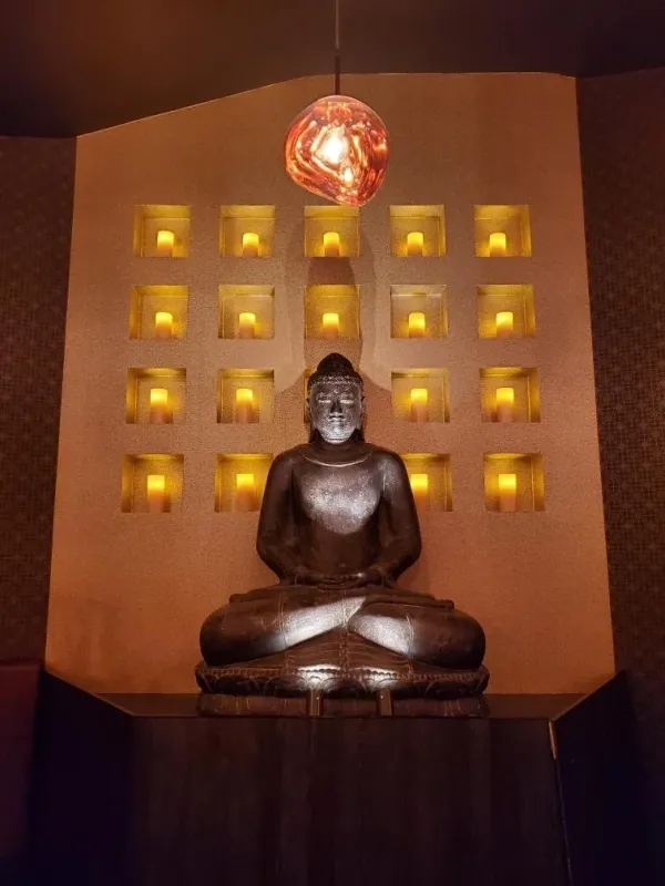 A Buddha statue with yellow lights and candle